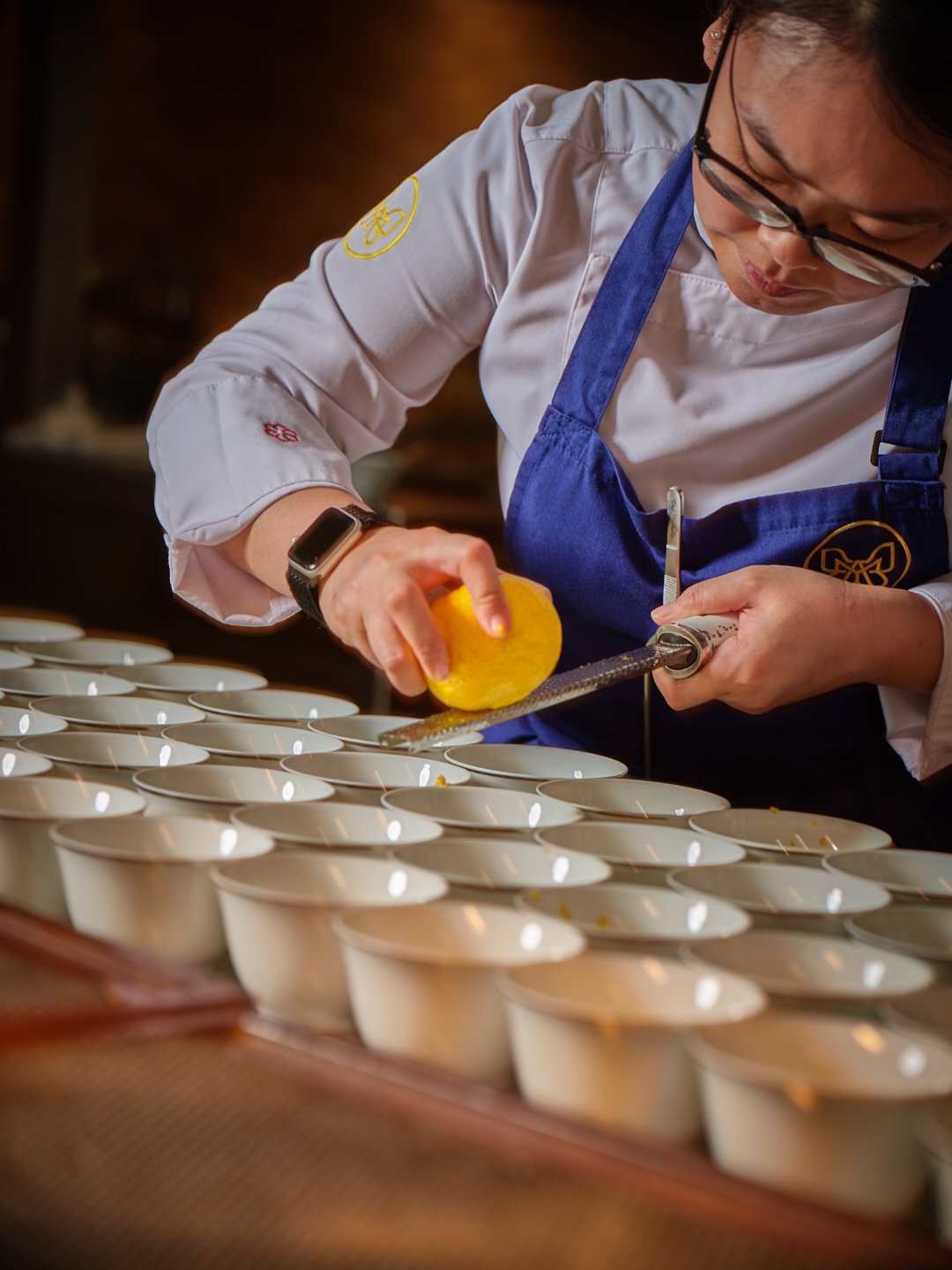 Chef Michelle Goh preparing service for a private event, wearing the Mia apron